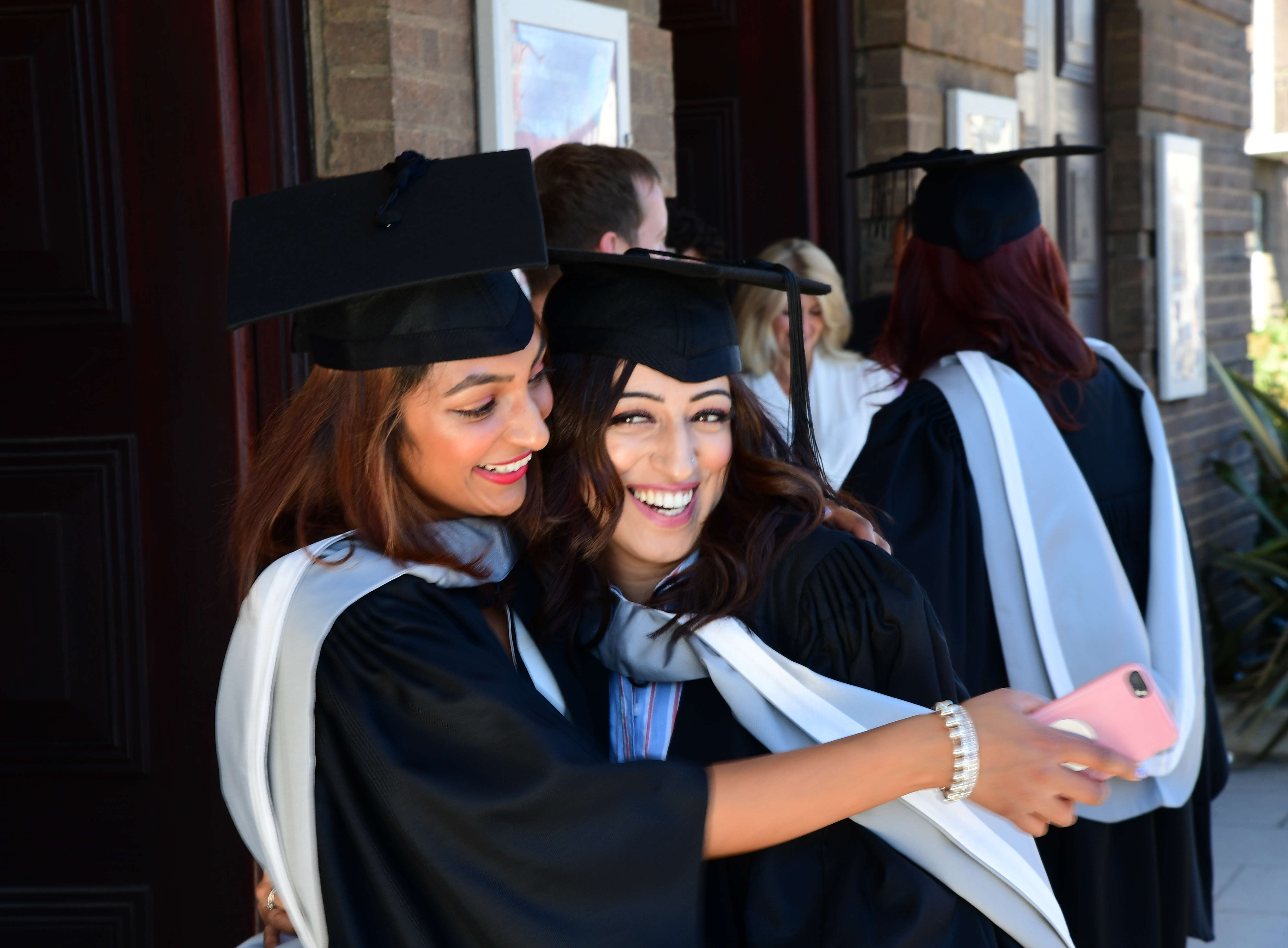 Two girls smiling and hugging in their cap and gown