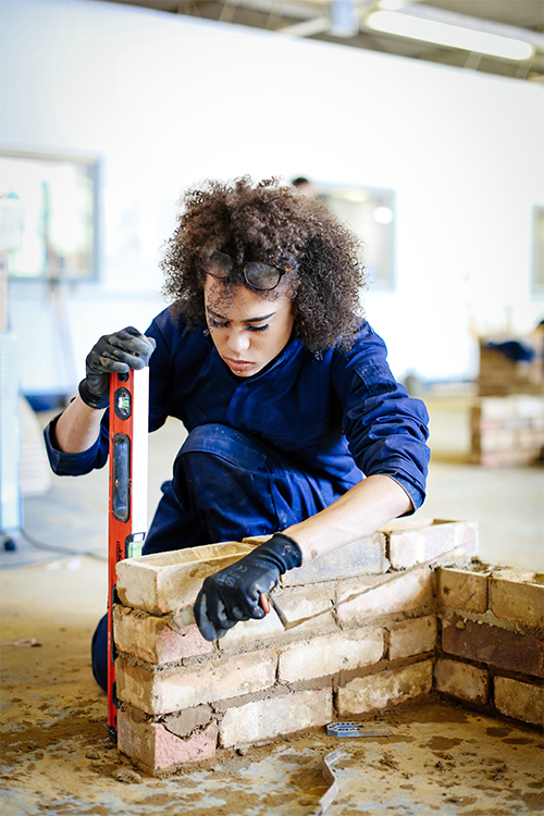 Student checking brick wall with spirit level measurer