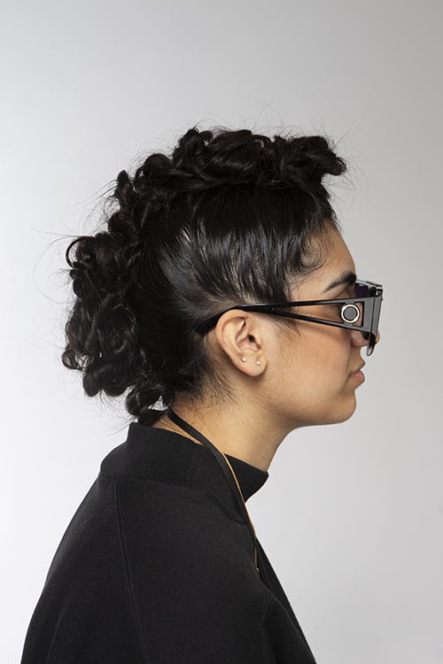 Student wearing sunglasses facing side-on with a curly Mohican hairstyle