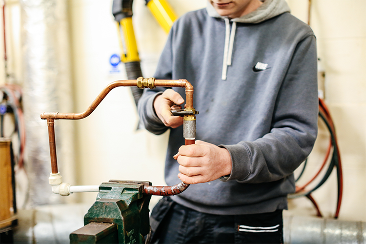 Student fixing pipes together