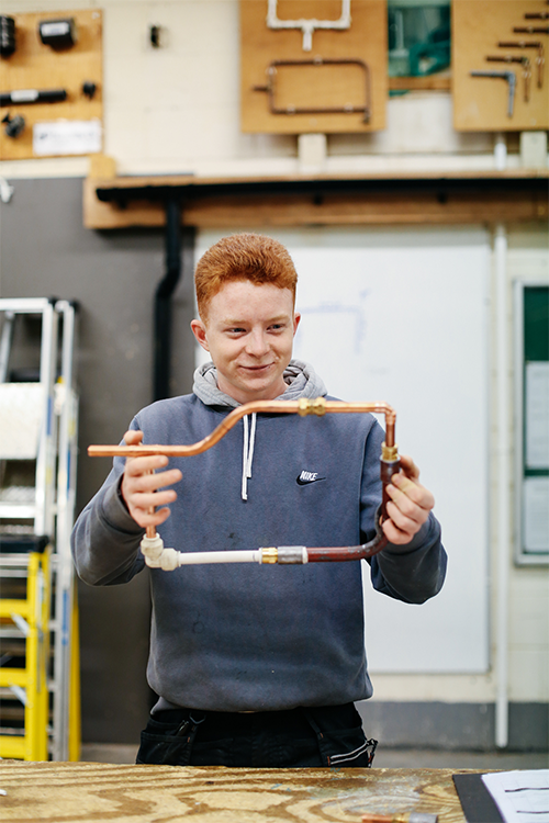 Student fixing pipes together
