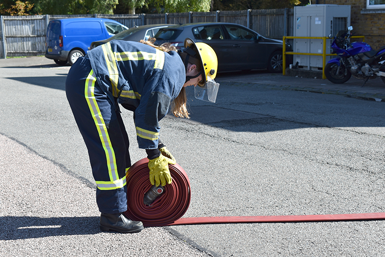 Student rolling a fire hose