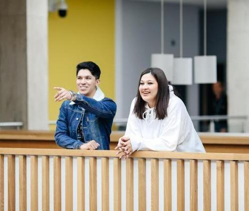 Two student laughing and smiling on a bridge