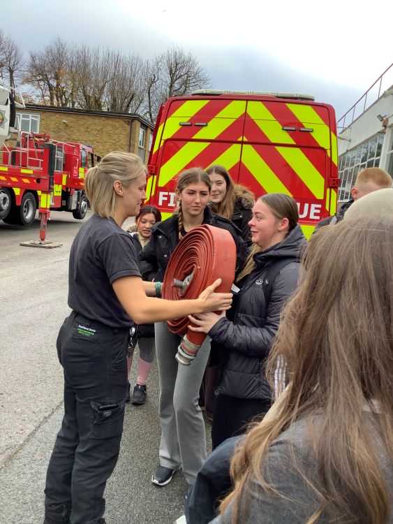 students looking at a fire hose