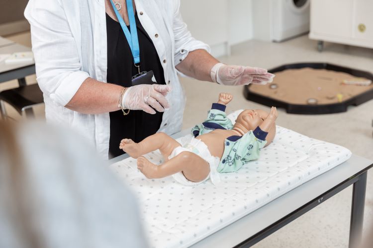 teacher demonstrating chaning a doll's nappy