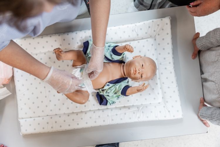 student changing a doll's nappy