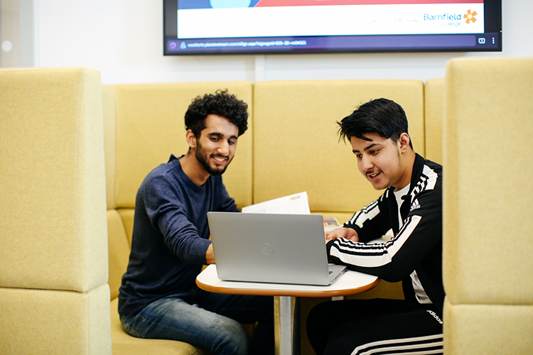 Students in a booth revising on a laptop